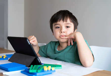 Kid learning math online on tablet and using plastic block counting number, Child boy studying math...