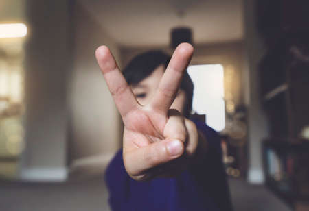 Blurry face of little boy pointing  two fingers at camera, Selective focus of kid primary school boy showing his finger, Child counting number fiv, Education or Toddler development conceptの写真素材