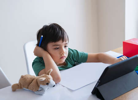 New normal life,Kid using tablet learning at home,Child boy serious face studying or searching the...
