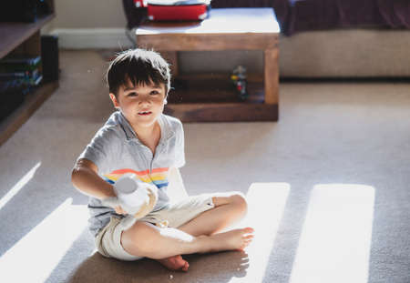 Kid playing alone with dog toy in living room with morning sun shining through the windowの写真素材