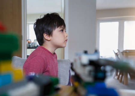 Candid shot Kid sitting on sofa watching TV in living room, Child looking excited while watching TV...