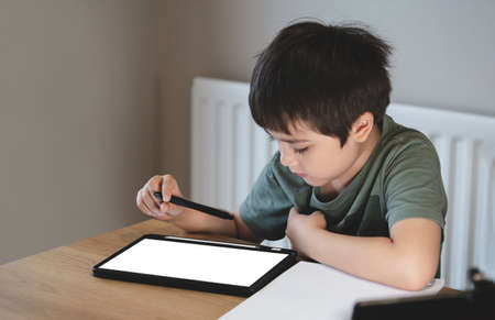 Kid self isolation using tablet for his homework,Child boy using digital tablet searching information on internet during covid 19 lock down,Home schooling,Social Distance,E-learning online educationの写真素材