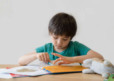 Active boy selecting his favorite colour  pen for painting,School kid using a pen drawing on white paper, child relaxing at home,Home schooling, Distance education,E-learning conceptの写真素材