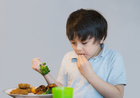 7 year old kid boy having homemade chicken nuggets potato and broccoli for Sunday dinner at home, Happy child eating lunch, Children eating healthy and Fresh food, Healthy life style conceptの写真素材