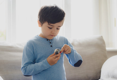 Portrait happy kid playing with colourful plastic toys alone in living room, New normal life style Child boy relaxing at home with bright light in the morning,Positive child, happiness and healthy kidの写真素材