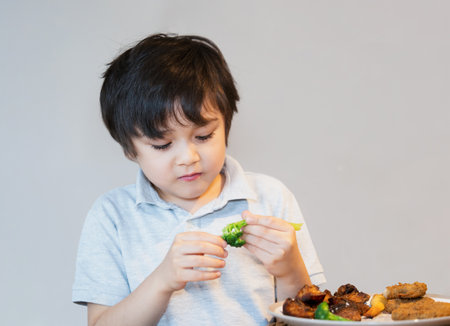 7 year old kid boy having homemade chicken nuggets and roat potato and broccoli for Sunday dinner at home, Happy child eating lunch, Children eating heathy and Fresh food, Healthy life style conceptの写真素材