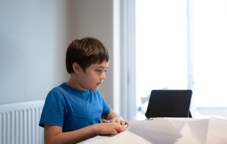 Happy school Kid learning paper art origami lesson, Child boy having fun doing Art and Craft at home, Home schooling conceptの写真素材