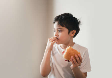 Hungry young boy eating homemade bacon sandwiches with mixed vegetables, Healthy Kid having...