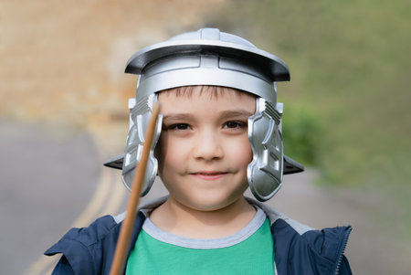 Happy boy wearing lobster-tailed pot helmet costume pretending to be a legionary  soldier, Active kid playing outside in the park field on Spring, Child having fun doing outdoors activity in  Summerの写真素材