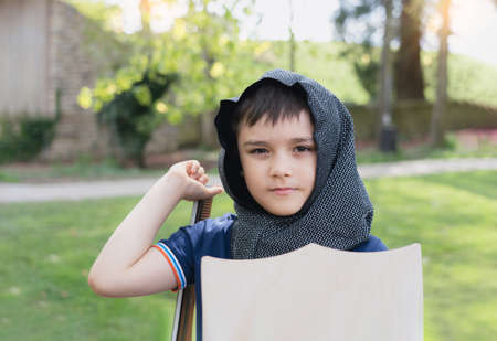 Young boy wearing knight costume holding sword shield standing in the park, Happy kid pretending to be a Medeival warrior, Active kid having fun playing or doing outdoor activityvon Spring or Summerの写真素材