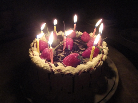 birthday cake with sweet strawberry and light candle in the darkの写真素材