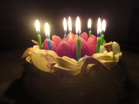 birthday cake with sweet strawberry and light candle in the darkの写真素材