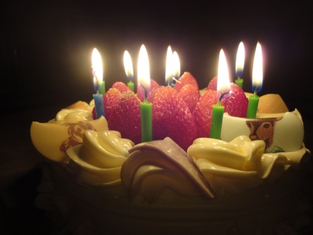 birthday cake with sweet strawberry and light candle in the darkの写真素材