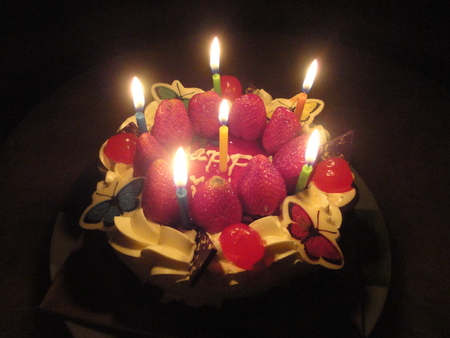 nice sweet cherry and strawberry cake with candle light in the darkの写真素材