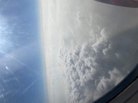 clouds in the blue sky as seen through window of an aircraftの写真素材