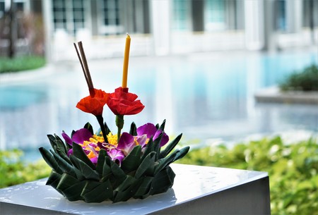 A krathong made from banana leaf and some flowers, candle and incense are needed, laying on near the...