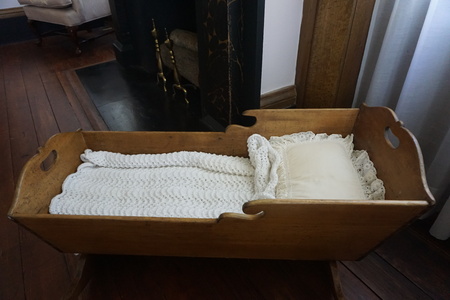 An antique wooden baby bed with white sheet and white pillowcase standing in the big bed room looks beautiful and neat , GA USAの写真素材
