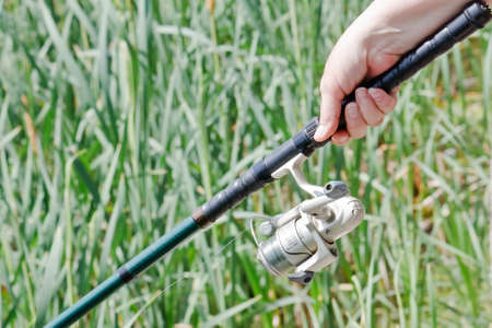 Closeup of a fisherwoman hand holding a fishing rodの写真素材
