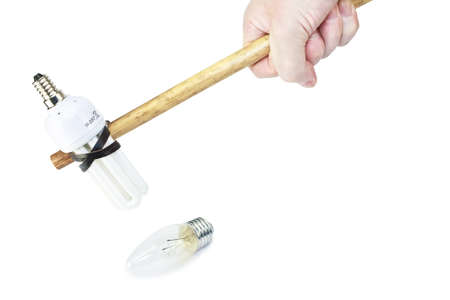 Male hand breaks old electric light bulb with hammer made modern fluorescent bulb isolated on white as energy saving conceptの写真素材