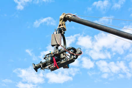 Professional tv camera on a crane in action against blue skyの写真素材