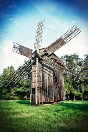 Old wooden traditional ukrainian windmill over blue sky with clouds - old photo style