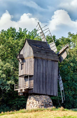 Old wooden traditional ukrainian windmill over blue sky with cloudsの写真素材