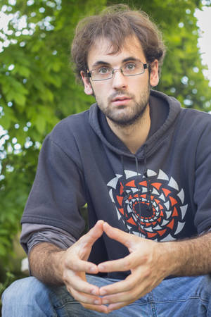 Portrait of young boy with beard and glasses, dressed in sweatshirt with drawing; In the field, outdoors. Selective focusの写真素材
