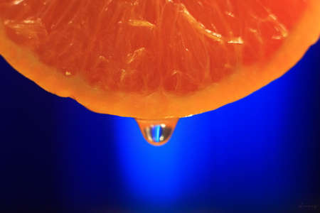 orange slice with juice drop and blue backgroundの写真素材