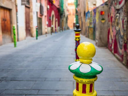 Deserted street of Tarragona`s historic center in Catalonia, Spain, with colored painted pylonsの写真素材