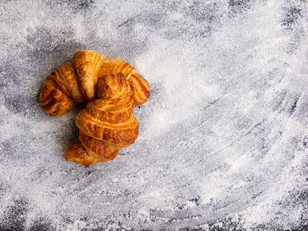 Two simple fresh homemade butter croissants isolated on white flour background. Homemade pastry concept.の写真素材