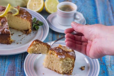 Hand eating lemon cake with coffee. Homemade cakes on a blue background. Copy space for text....