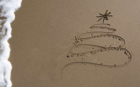 Christmas tree drawn in sand at the beach. Holiday concept.の写真素材