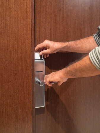 Cropped view of man holding hotel card while opening hotel door