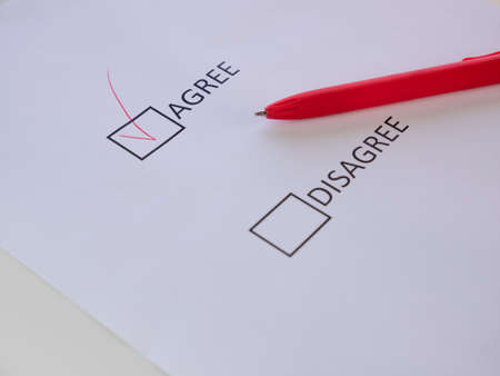 Agree and disagree check boxes on the white sheet mark agree with red pen. Selective focus on the...