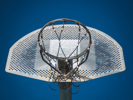 Basketball backboard and basket with palm trees on bright blue sky background. Empty and closed sports field during quarantineの写真素材
