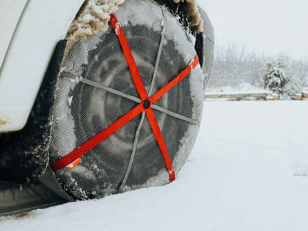 Detail of a car wheel with textile wheel snow chains driving through a frozen and snowy fieldの写真素材