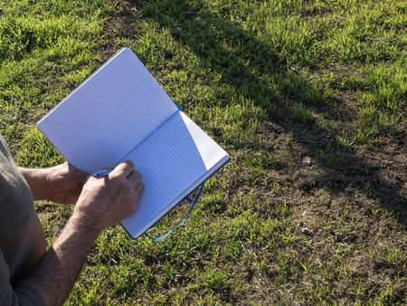 Mature farmer taking notes in a notebook in the field. Agricultural concept.の写真素材