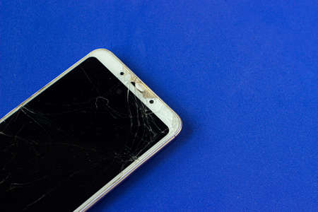 A view of the broken screen of a modern smartphone with numerous cracks