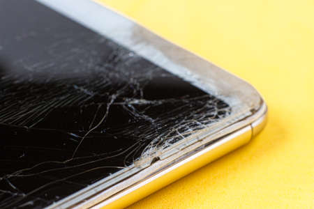 A macro view of a broken screen of a modern smartphone with numerous cracks