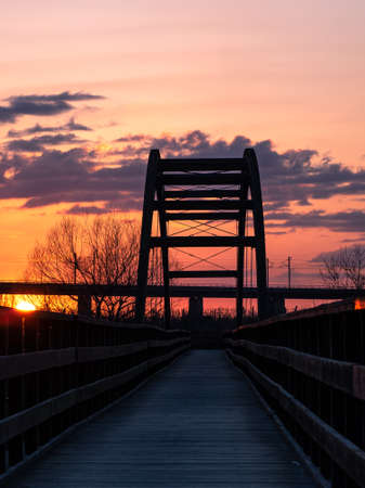 Red sunset sky with a wooden bridge in the form of an arch.