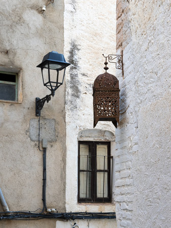 Typical street lamp in a small street of white houses that contrasts with an old wooden street lamp.の写真素材