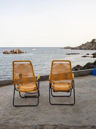 Yellow deckchairs facing the sea on the Costa Brava beach, (Spain). Vacation concept.の写真素材