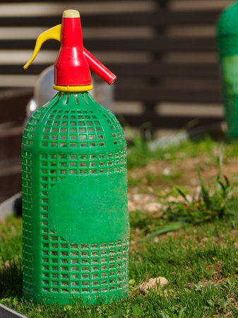 Old glass bottle siphon wired with insulated plastic protector over a garden.の写真素材