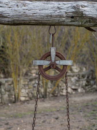 Old well made with stones, wood and wheel pulley in the gardenの写真素材