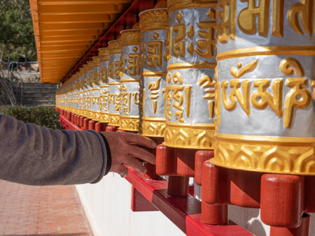 Man spinning prayer wheels. The wheels have thousands of mantras inside symbolizing the sound of love and compassionの写真素材