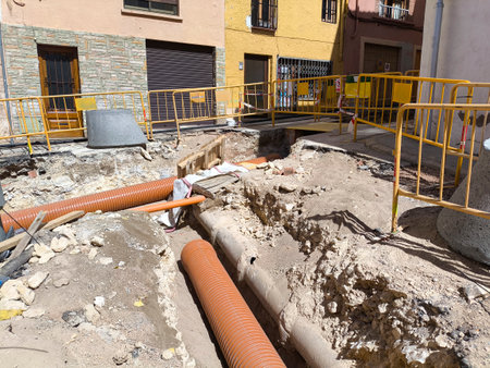Trench with new pipes in the ground of a residential street in a village in Spain. Concept of public works.の写真素材