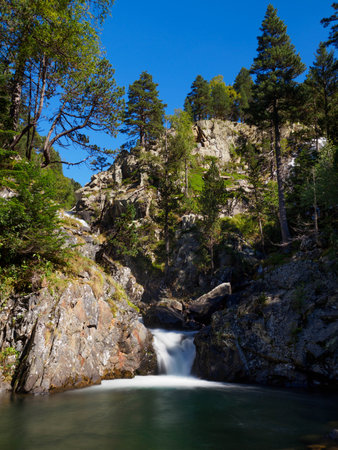 A mountain river forms waterfalls between rocks and vegetation with autumn colors.の写真素材