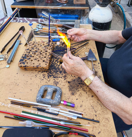 Close-up of a glass artisan heating glass to make different pieces of jewelry.の写真素材