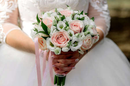 The bride holds a bouquet of roses in her handsの写真素材