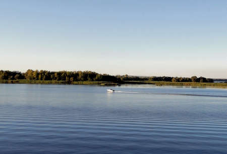A view of a boat in the middle of a lake with trees on the horizon